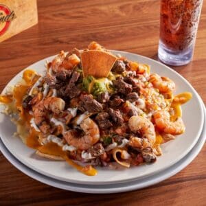 A plate of nachos topped with shrimp, steak, melted cheese and guacamole at Golden Legends