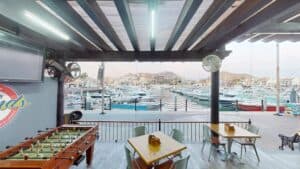 The covered terrace at Golden Legends with a foosball table and tables facing the boats in the Cabo San Lucas marina
