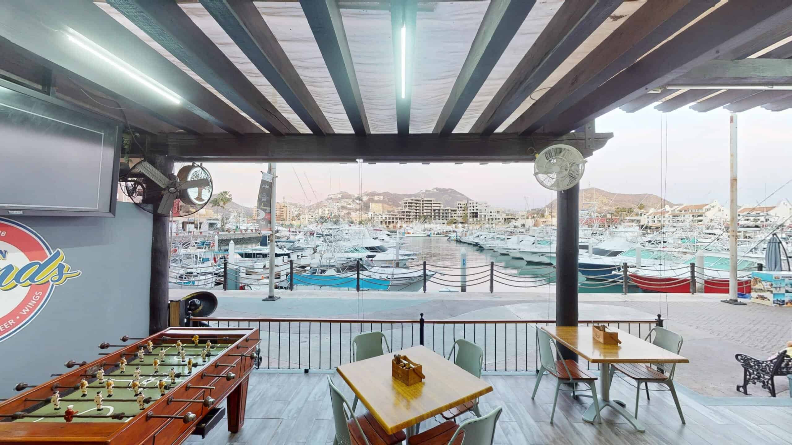 The covered terrace at Golden Legends with a foosball table and tables facing the boats in the Cabo San Lucas marina
