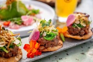 Tuna tostadas topped with seaweed salad, crispy leeks, watermelon radish and a marigold at The Green Room
