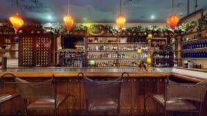 The long wooden bar at Jack's Steak House, with shelves of bottles and a wine rack under red glass lamps