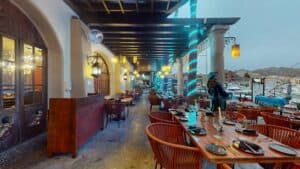 The covered terrace of Jack's Steak House on the Cabo San Lucas marina boardwalk, with a pirate figure by the railing and yachts behind
