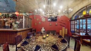 A large round table with a coin-mosaic top under a crystal chandelier at Jack's Steak House, beside windows onto the marina