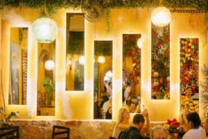 Diners beneath a yellow wall of backlit mirrors and glass-float lamps in the dining room at Jazmin's Restaurant