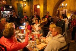 A mariachi band playing beside a tiled table of guests inside Jazmin's Restaurant