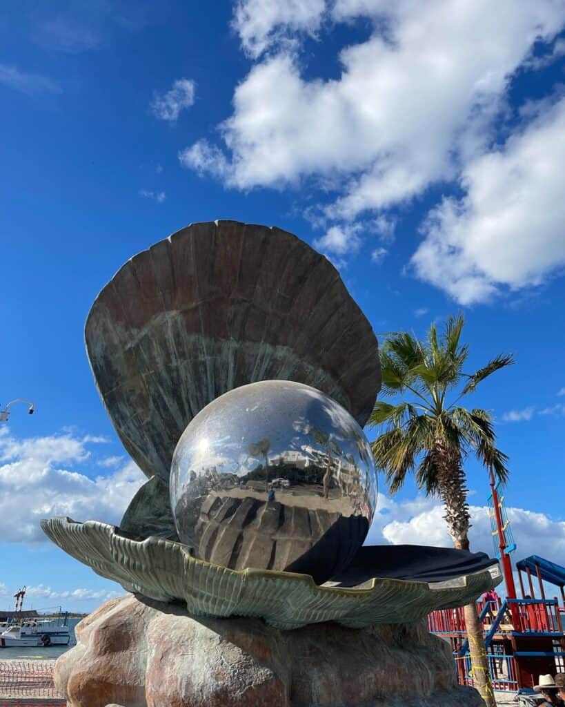 The pearl-in-a-shell sculpture on the La Paz malecón with palms and blue sky