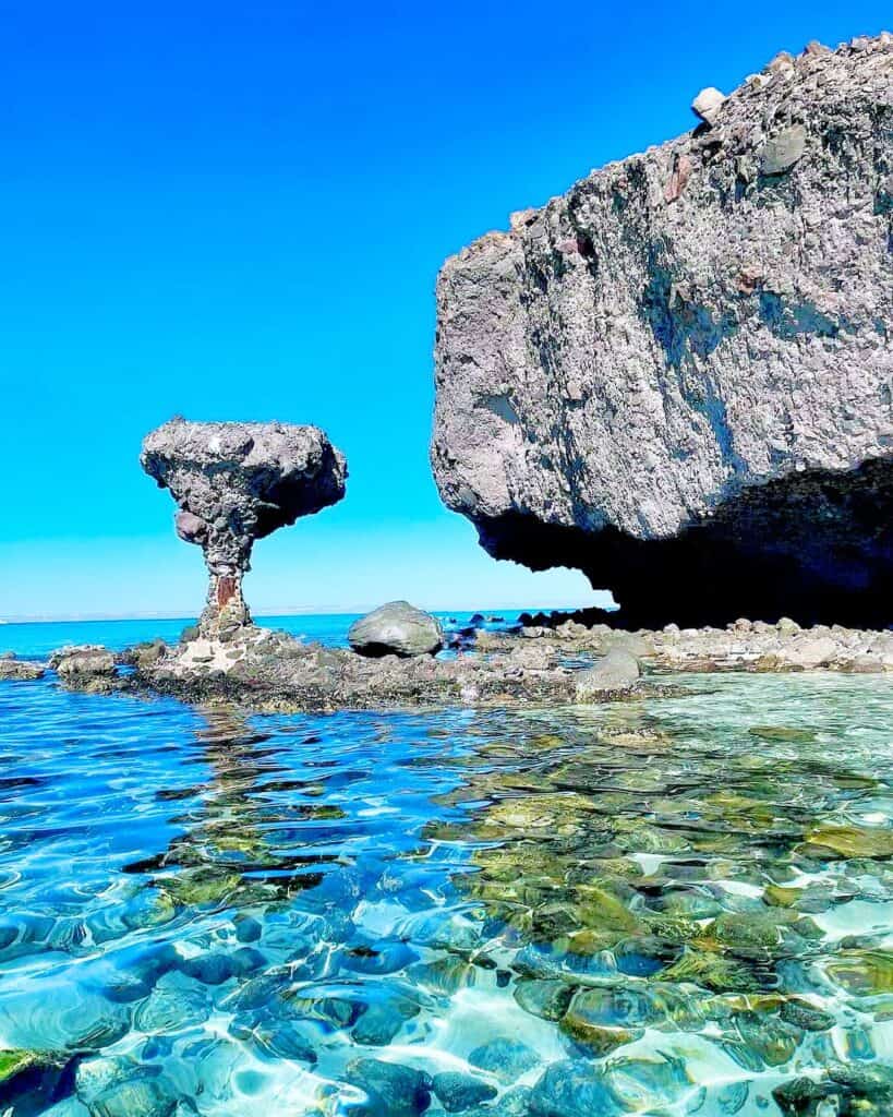 El Hongo, the mushroom rock of Balandra, seen from the turquoise shallows with the cliff behind
