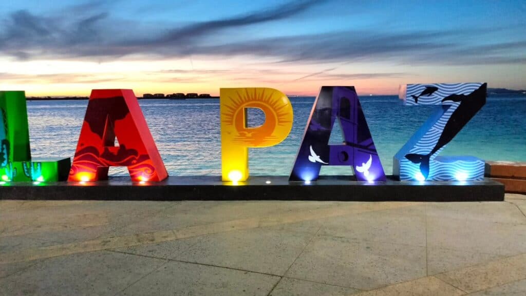 The illuminated LA PAZ letters on the malecón at sunset, with the bay behind