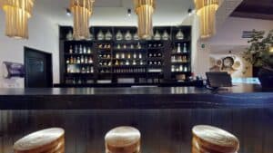 The bar at Los Deseos, with carved wooden stools and backlit shelves of bottles