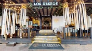 The entrance steps of Los Deseos under its lit sign, with ribbon lanterns hanging over the terrace