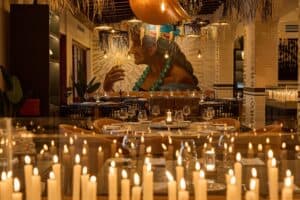 Candlelit tables at Los Deseos in front of a large mural of an elderly woman holding a candle