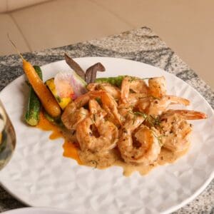 Shrimp in a creamy orange sauce with roasted baby vegetables, served at Los Deseos