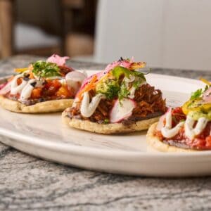 Three sopes topped with beans, shredded meat, cream, pickled onion and radish at Los Deseos