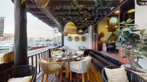 The covered terrace at Los Deseos, with rattan lamps and set tables beside the yachts of the Cabo San Lucas marina