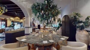 A tree hung with handwritten paper tags above a round stone-topped table in the dining room at Los Deseos