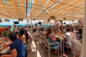 Guests at lunch on a shaded terrace at Mango Deck, with the bay in the background