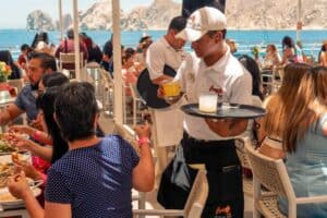 A Mango Deck server bringing drinks to diners on the Solarium terrace, with the Arch and Land's End across the water