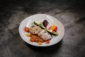 A plated fish fillet with red sauce, grilled zucchini, roasted beets and cherry tomatoes at Monte Cardón