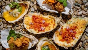 Baked oysters with crisp bacon, fried oysters and oysters in broth on the half shell over pebbles at Oystera