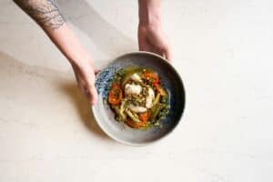 A bowl of burrata with tomatoes and crushed pistachios being set down at Palmerio