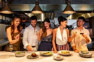 Friends toasting with wine over shared plates at the chef's counter at Palmerio
