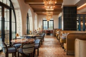 The indoor dining room at Palmerio, with leather banquettes, brick floors, arched windows and woven pendant lamps