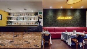 The bar shelves at Presto next to a red banquette and a La Vita e Bella neon sign on a green wall
