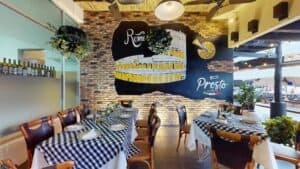 The covered terrace at Presto, with a Rome and Colosseum mural above tables set in black-and-white check and the marina walkway beyond