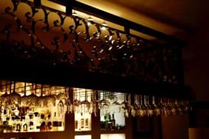 The bar at Puerta Vieja, with hanging wine glasses under a wrought-iron rack and backlit bottles