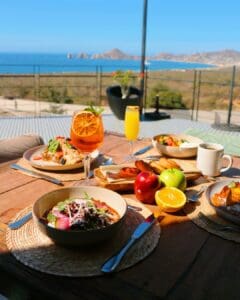 Breakfast plates, fresh fruit, coffee and cocktails on the Puerta Vieja terrace, with the Arch across the bay