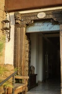 The carved antique wooden doors at the entrance of Puerta Vieja, under the Restaurant and Bar sign marked Since 2003
