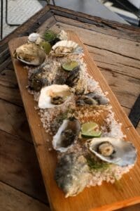 Fresh oysters on the half shell with lime on a bed of rock salt, served on a wooden board at Puerta Vieja