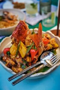A crispy fried whole fish with chilies, bell peppers and basil in a white bowl at Talay