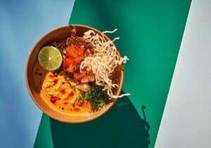 A bowl of khao soi at Talay: curry broth with fried soft-shell crab, crispy noodles, herbs and a lime half