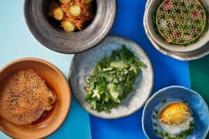 Five Thai dishes at Talay seen from above on a blue table, including a herb salad and mango sticky rice