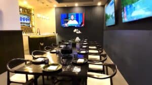 The private dining room at The Woods Cabo, a long table set for a group under wall-mounted TVs