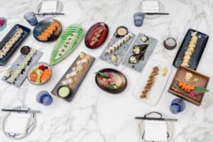 Maki rolls, nigiri and sashimi from the sushi bar laid out across a marble table at The Woods Cabo