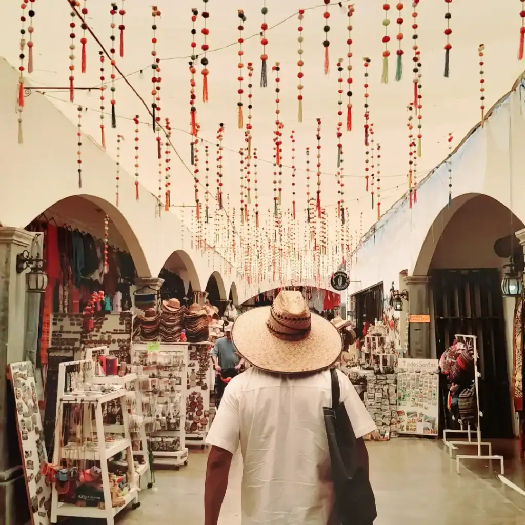 A visitor in a straw hat walking through a market under the arches in Todos Santos
