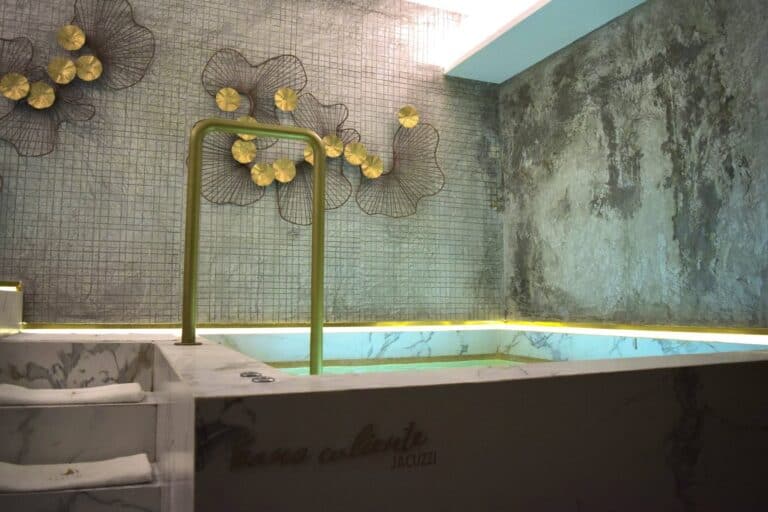 Hot tub in the Amura Spa hydrotherapy area with a brass handrail and gold wall art