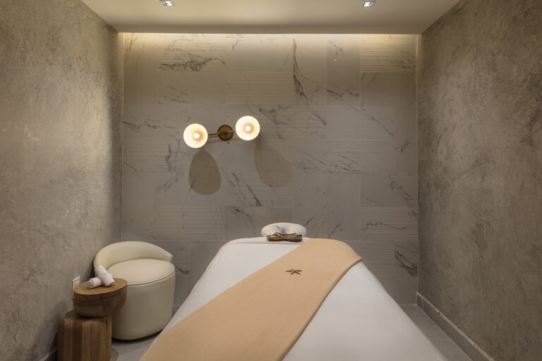 Single massage room at Amura Spa with a marble wall and soft sconce lighting
