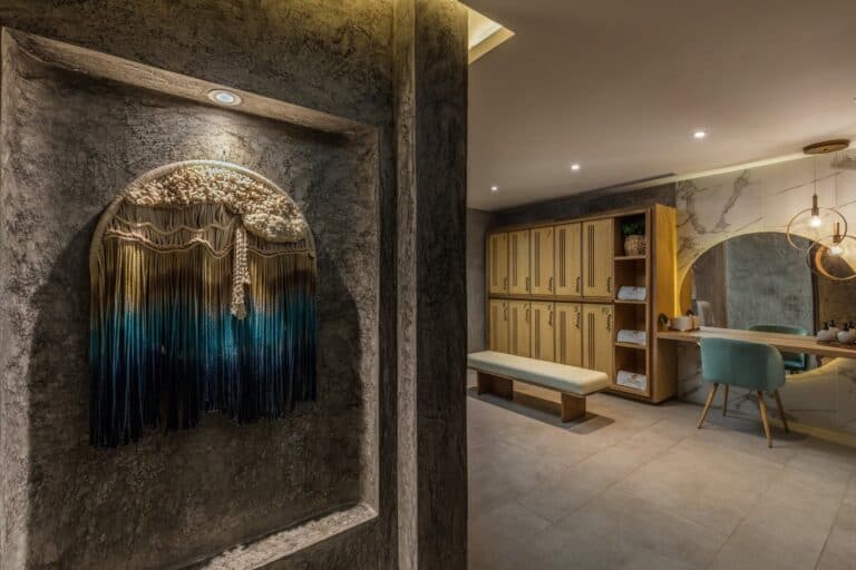 Amura Spa locker room with wooden lockers, a vanity and a woven wall hanging