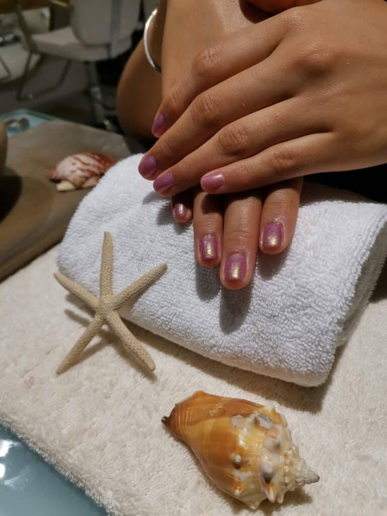 Fresh manicure resting on a towel next to a starfish and a seashell at Amura Spa
