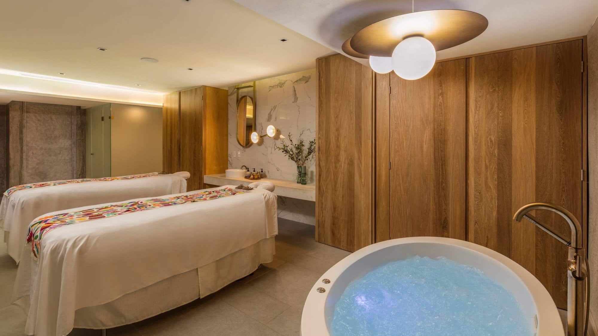 Couples treatment room at Amura Spa with two massage tables and a round whirlpool tub