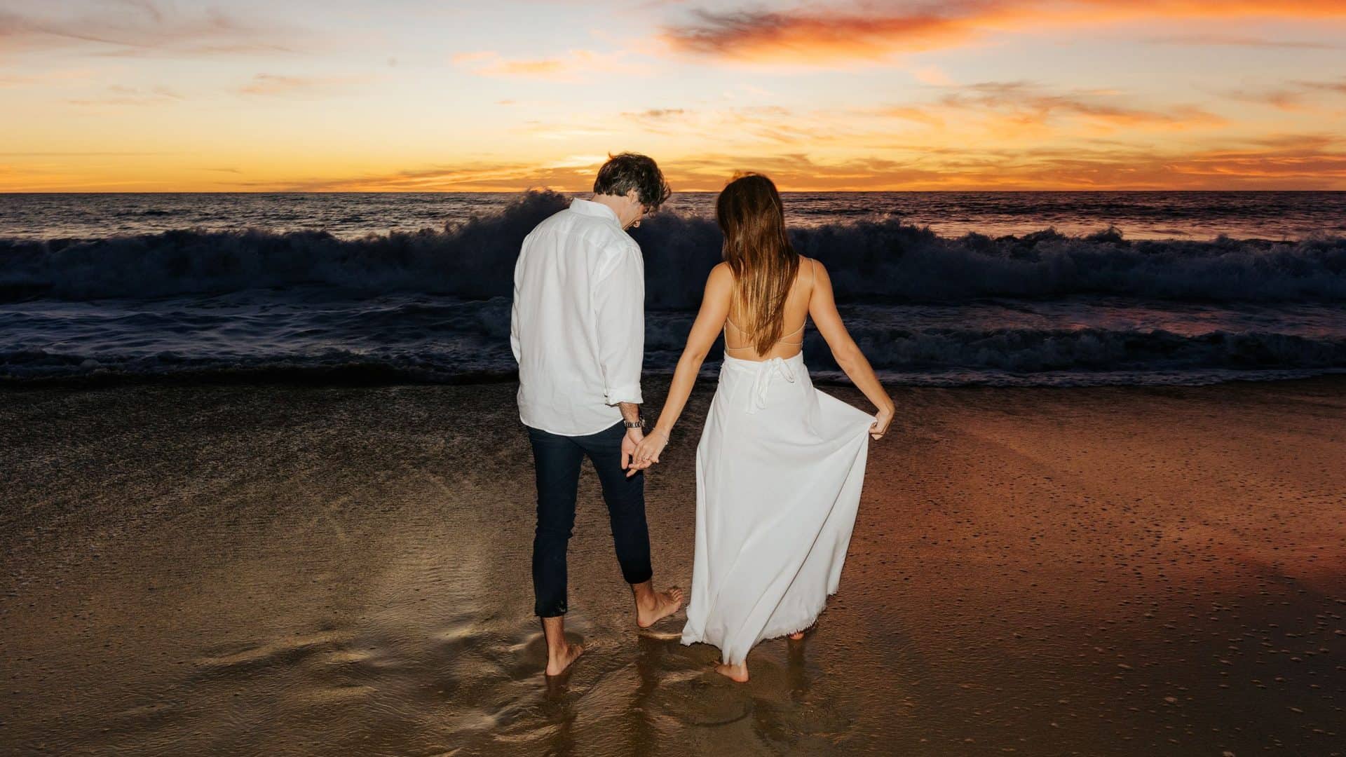 Couple holding hands on the shoreline at sunset in Los Cabos