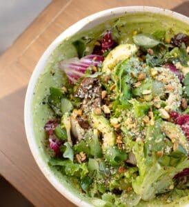 A green salad with avocado, pistachios and seeds in a ceramic bowl at Cream