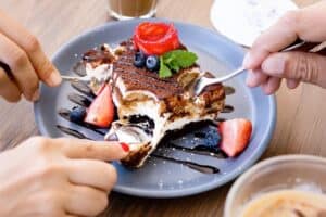 Two forks in a layered cocoa and cream dessert with strawberries and blueberries at Cream
