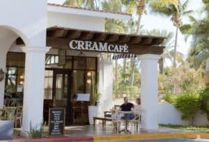 Guests at a table on the front terrace of Cream Palmilla at The Shoppes at Palmilla, under white arches