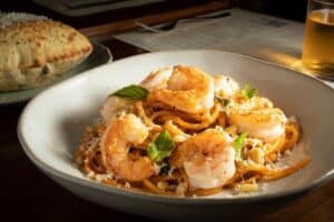 Shrimp pasta with pine nuts and basil in a wide bowl at Cream, with bread on the side