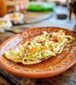 Fried quesadilla topped with lettuce, carrot, cream and cheese at Las Guacamayas
