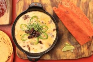 Queso fundido in a cast-iron skillet with chicharrón de queso at Las Guacamayas